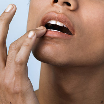 Closeup of a woman applying a lip balm on her lip